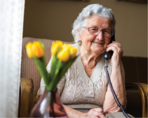 Older smiling adult talking on a phone
