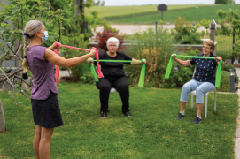 Older adults in an outdoor setting participating in an exercise class while maintaining social distance