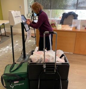 woman in apartment building lobby delivering meals to older adults