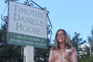 Social worker Heather Berry standing outside the Timothy Daniels House, next to the building sign